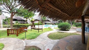 A tropical resort with thatched-roof structures, a swimming pool, and stone pathways. - Harbour Key Cottages (Malindi)