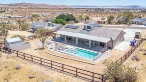 Et moderne hus med swimmingpool, solpaneler og et ørkenlandskab i baggrunden.