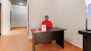 A man in a red shirt sitting at a desk with a sign that reads "OYO".