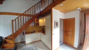 Une cuisine compacte avec des meubles en bois, une cuisinière intégrée et un escalier en bois menant à un niveau supérieur.