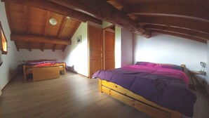 Une chambre à coucher avec un lit en bois, un petit banc en bois et une porte donnant sur une autre pièce.