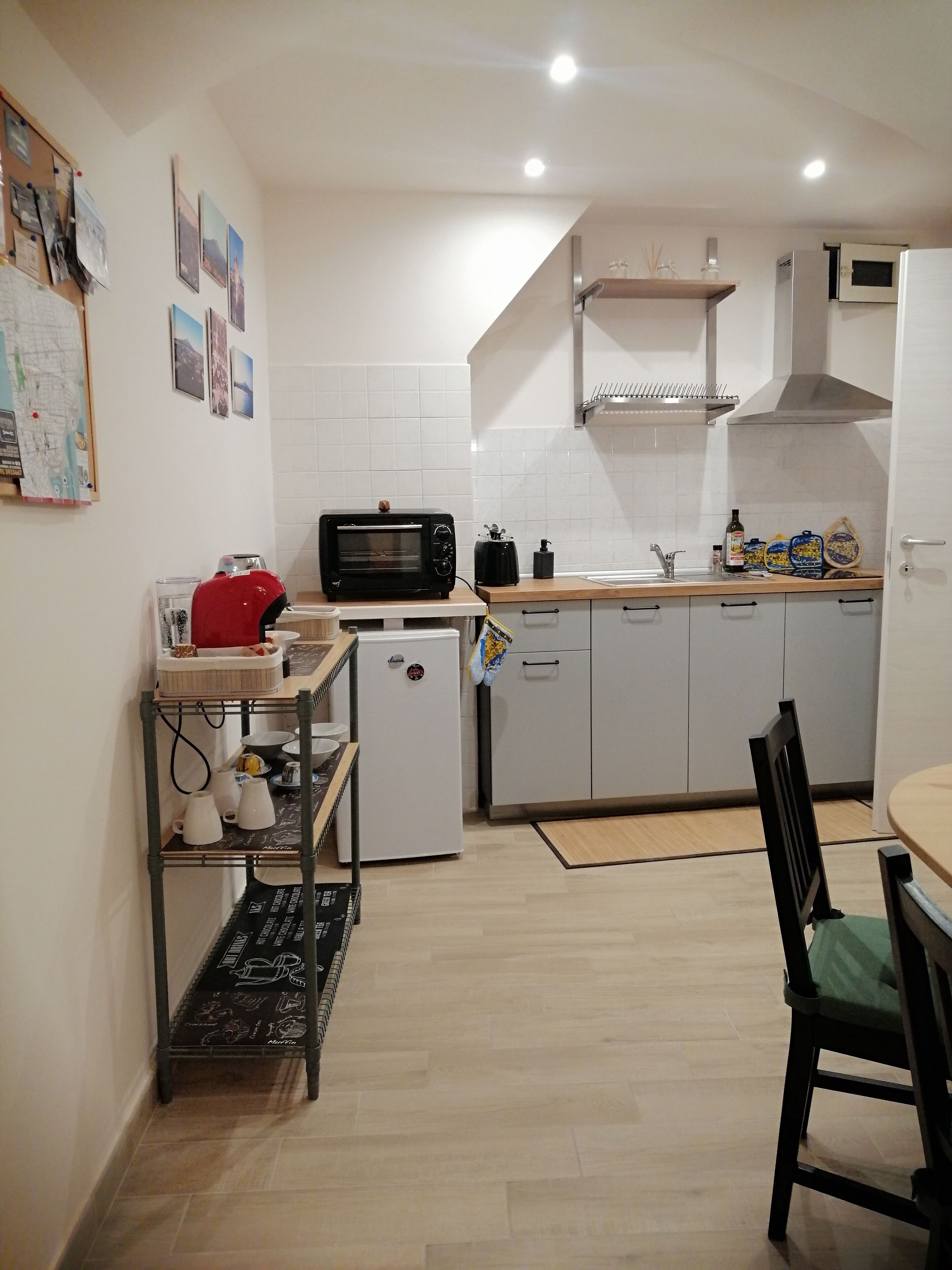 A compact kitchen with white cabinets, a microwave, a toaster, and a small refrigerator.
