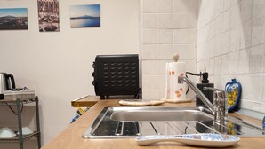 Eine Küche mit modernem Herd, Spüle und einer Arbeitsplatte, auf der sich ein Wasserkocher und eine Flasche befinden.