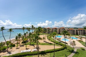 Un complexe hôtelier doté d’une plage, de palmiers et d’un espace piscine.