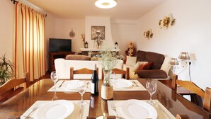 A dining area with a table set for four, a wine bottle, and a vase with flowers. - 1200 Villa el Barco (Nerja)