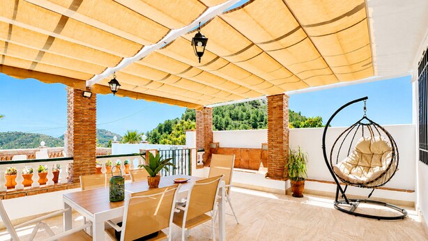 An outdoor patio with a table and chairs, a hanging chair, and potted plants. - 1200 Villa el Barco (Nerja)