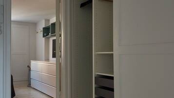 Ein Flur mit Holzboden, der zu einem Schlafzimmer mit Bett und Kleiderschrank führt.