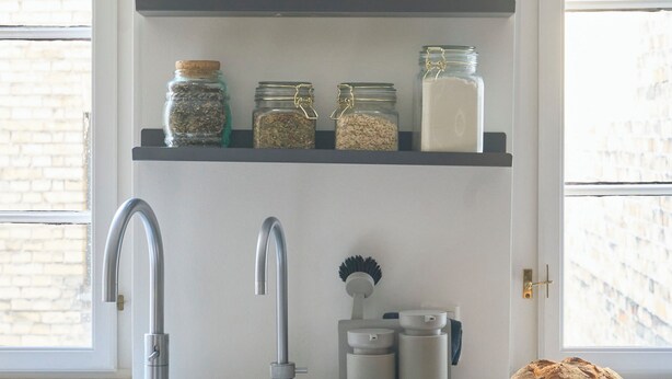 A kitchen with a sink, two shelves above it holding jars and containers, and a loaf of bread on the counter. - Perfect location, cosy and stylish and with one of the largest bathrooms i town (København)