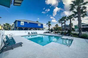 Relax by the pool surrounded by palm trees and lounge chairs.