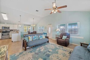 A spacious living room with a sofa, armchair, and a ceiling fan.