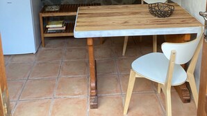 Une cuisine compacte équipée d’un four à micro-ondes, d’un petit réfrigérateur, d’une table en bois et d’une chaise blanche.