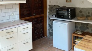 Une cuisine de taille réduite avec des meubles blancs, un petit réfrigérateur, un four à micro-ondes et une porte en bois.