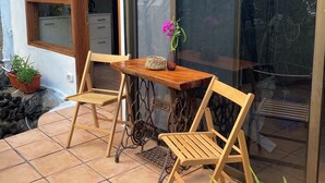Une terrasse avec deux chaises en bois, une petite table et un pot de fleurs.