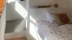 Une chambre à coucher avec un lit, un tableau encadré et une salle de bain visible à travers une arche.