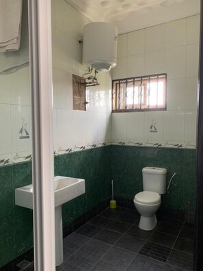 Bathroom features a pedestal sink, toilet, and window with metal bars.