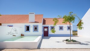 A modern building with a tiled roof, a swimming pool, and a small garden with a tree.
