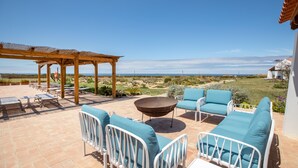An outdoor patio with a pergola, seating area, and a view of the landscape.