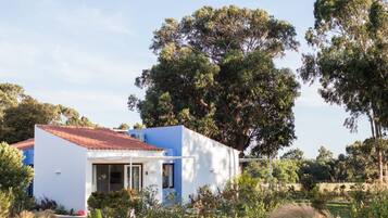 Un edificio blanco con tejado rojo, rodeado de abundante vegetación y árboles.