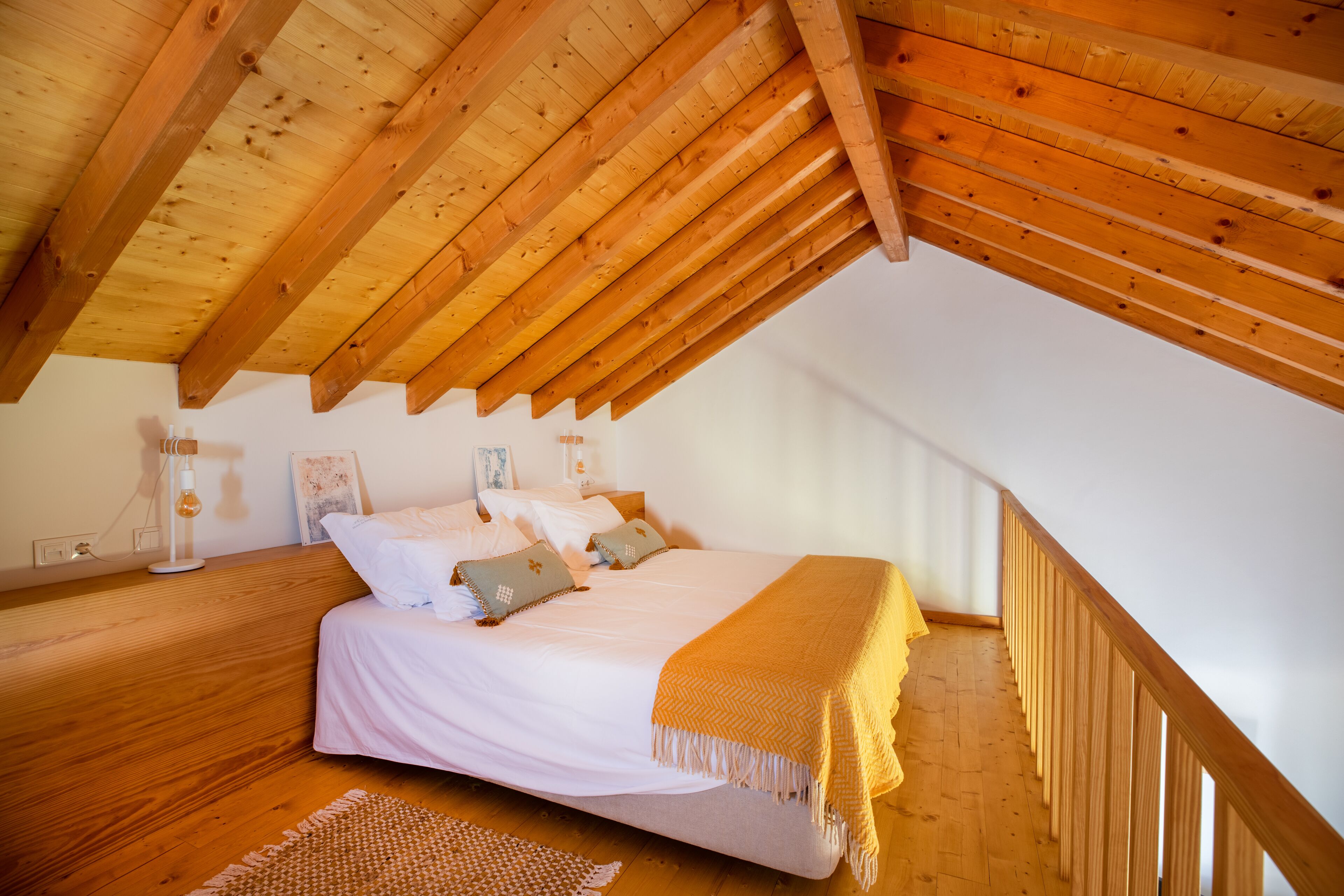 A bedroom with a wooden ceiling, a bed with white bedding, and a wooden floor.