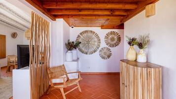 Ein gemütliches Wohnzimmer mit Holzboden, einem weißen Sofa, einem Holzstuhl und dekorativen Wandbildern.