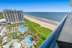 Ein Hotel mit einem großen Gebäude, einem Strand und einem Wasserpark.