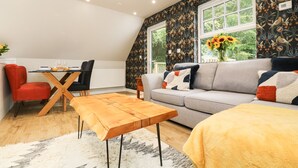 En hyggelig stue med spisebord, sofa og et vindue med udsigt over grøn natur.