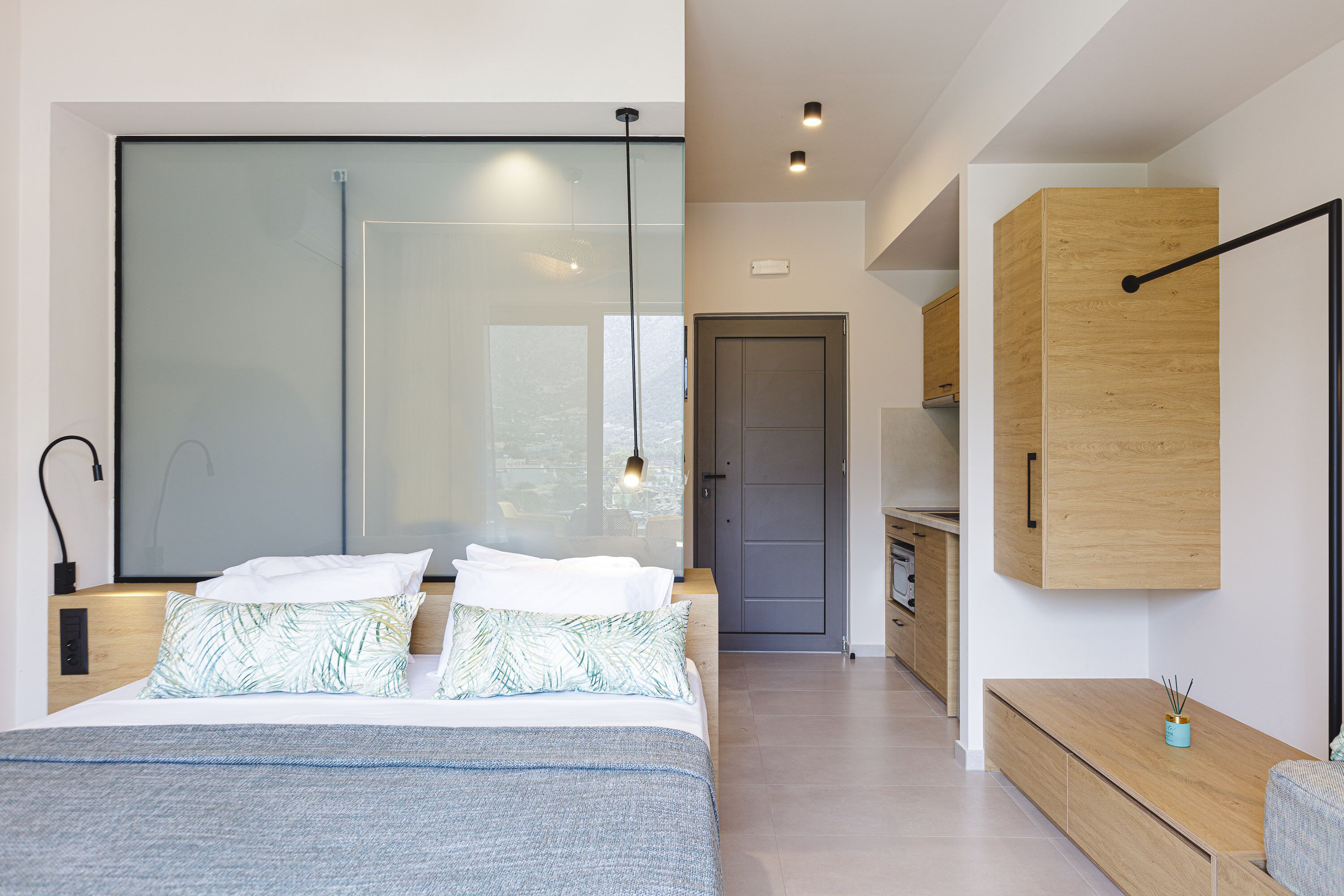 Un dormitorio moderno con una cama grande, un muro de cristal y un armario de madera.