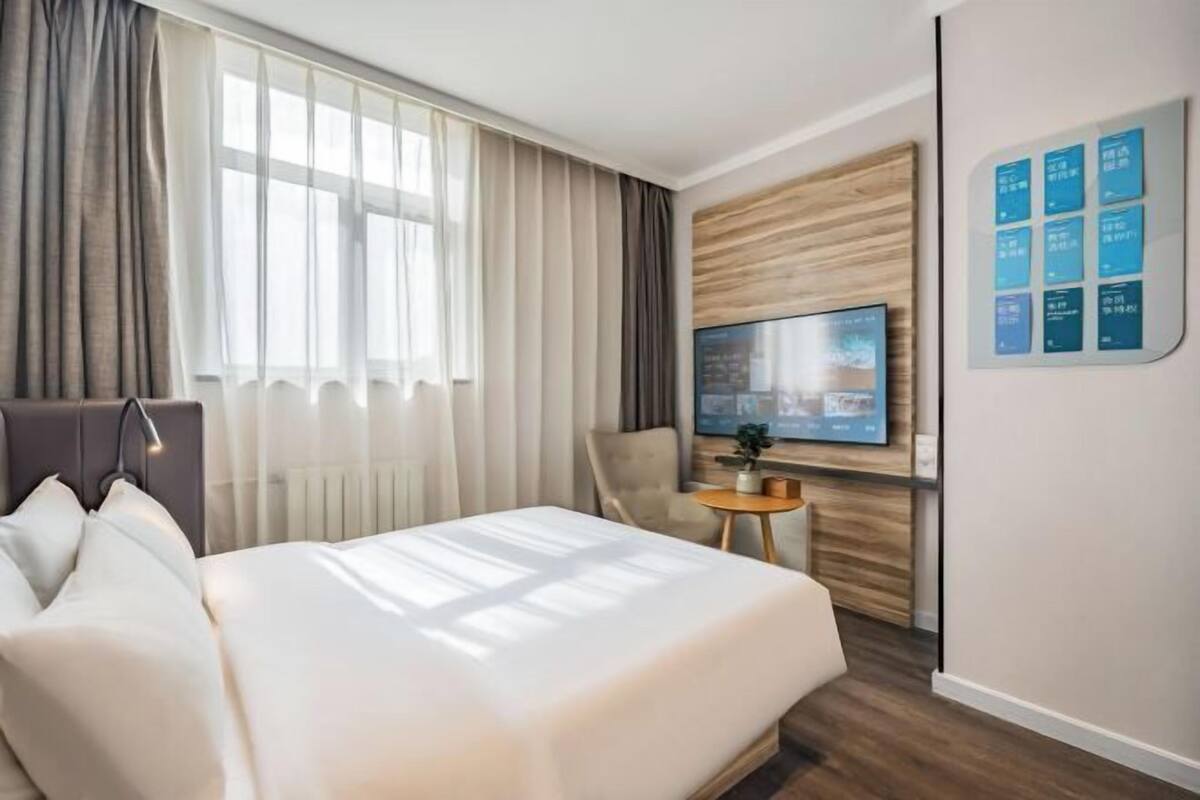 A hotel room with a bed, a TV, a small table, and a chair.