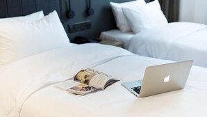 A neatly made bed with white linens, a laptop, and a magazine on it. - HanTing Premium Beijing South Railway Station Jiaomen East Subway Station Hotel (Beijing)