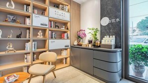 A modern reception area with a bookshelf, a reception desk, and a seating area. - HanTing Premium Beijing South Railway Station Jiaomen East Subway Station Hotel (Beijing)