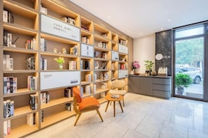 A hotel lobby with a large bookshelf, seating area, and a reception desk. - HanTing Premium Beijing South Railway Station Jiaomen East Subway Station Hotel (Beijing)
