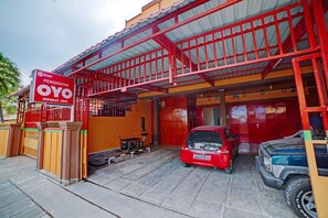 A red car parked in front of a building with a sign reading 'OYO Sepakat Jaya'. - OYO 90387 Sepakat Guest House (Medan)