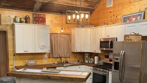 Una cocina con armarios de madera, un refrigerador de acero inoxidable, una estufa y una barra con taburetes.