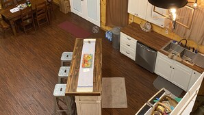 Una habitación acogedora de estilo cabaña con interior de madera, un comedor con mesa y sillas, una cocina con fregadero y armarios, y una puerta que dice 'The Porch'.
