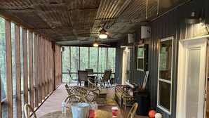 Un área de estar al aire libre cubierta con mesas y sillas de madera, un ventilador de techo y un letrero que dice "DEER'S BEER".