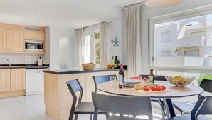 A modern kitchen with wooden cabinets, a built-in microwave, and a large window. - First floor apartment in Bellresguard complex, with pool, near the beach (Puerto Pollensa)