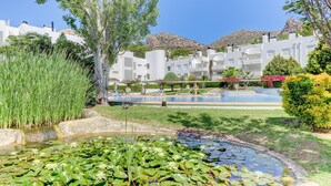 A pool area with water lilies, a white building, and a mountain in the background. - First floor apartment in Bellresguard complex, with pool, near the beach (Puerto Pollensa)