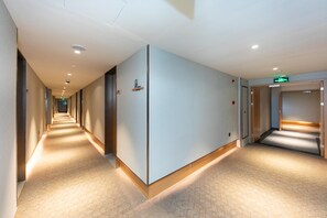 A hotel corridor with a long hallway, doors on the right, and a light-colored floor. - Ji Hotel (Shanghai)