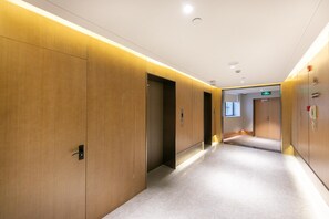 Corredor moderno de hotel com painéis de madeira, iluminação embutida e design limpo e minimalista.