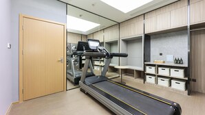 A modern gym with a treadmill, exercise bike, and storage units.