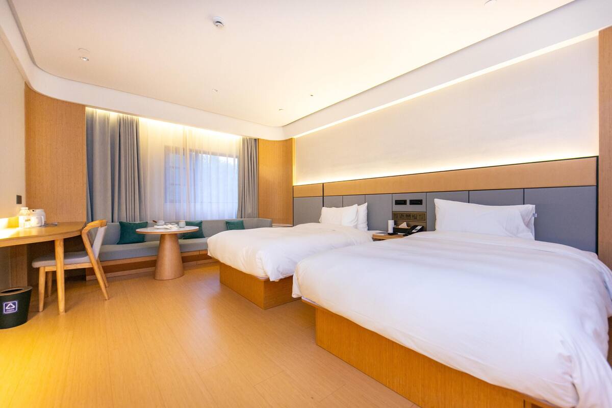 Une chambre d’hôtel avec deux lits, un bureau, une chaise et une petite table.