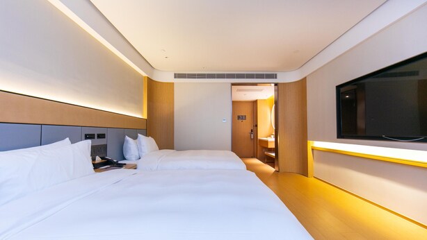 A hotel room with a large bed, bedside tables, a TV, and a door leading to a bathroom.