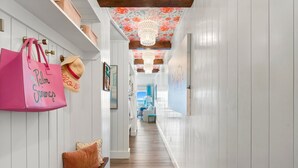 A hallway with white paneling, a wooden bench, a pink bag, and a straw hat. - 30A condo. Private beach. Incredible view! (Seacrest)