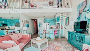 A spacious living room with a high ceiling, a balcony, and a kitchen area. - 30A condo. Private beach. Incredible view! (Seacrest)