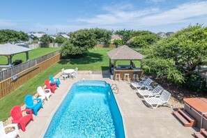 A rectangular swimming pool with a wooden deck, surrounded by lounge chairs and a barbecue area. - High Cotton - Old Nags Head Place, Ocean View, 325 Yds to Beach, Elevator, Pool, Hot Tub, Tiki Bar (Nags Head)