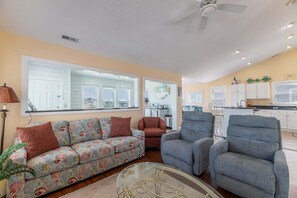 A living room with a sofa, armchairs, and a glass coffee table. - High Cotton - Old Nags Head Place, Ocean View, 325 Yds to Beach, Elevator, Pool, Hot Tub, Tiki Bar (Nags Head)