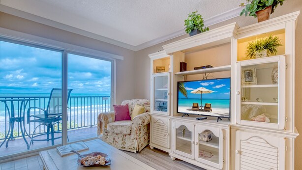 A living room with a large TV, a dining table, and a view of the ocean. - **DIRECT BEACH FRONT**GREAT LOCATION** 2 BEDROOM 2 BATH**AWESOME VIEWS** (Madeira Beach)