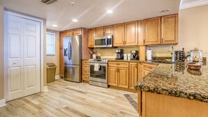 A kitchen with wooden cabinets, stainless steel appliances, granite countertops, and a tiled floor. - **DIRECT BEACH FRONT**GREAT LOCATION** 2 BEDROOM 2 BATH**AWESOME VIEWS** (Madeira Beach)