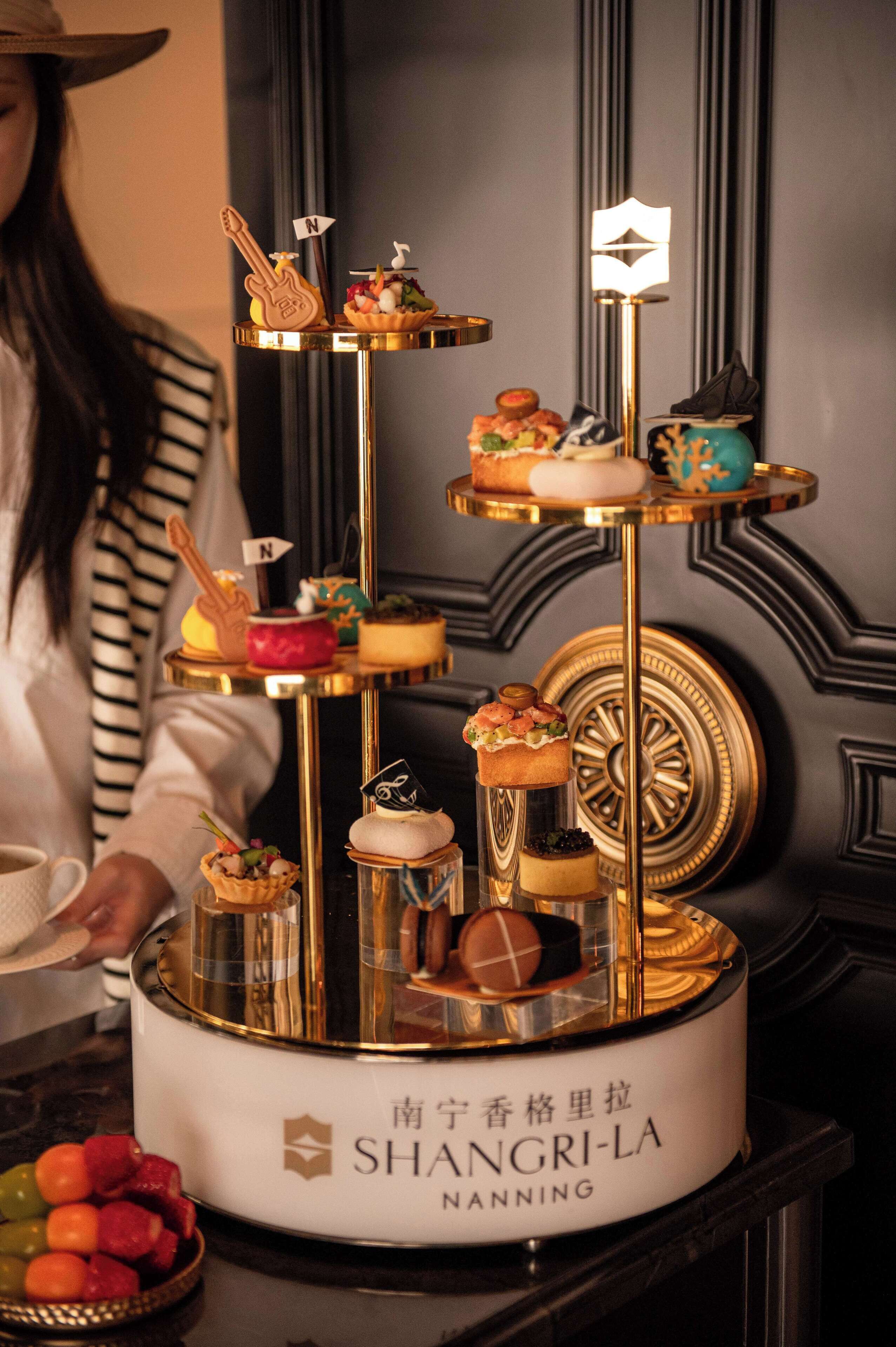 Una exhibición de postres con diversos pasteles y un letrero que dice 'SHANGRI-LA NANNING'.