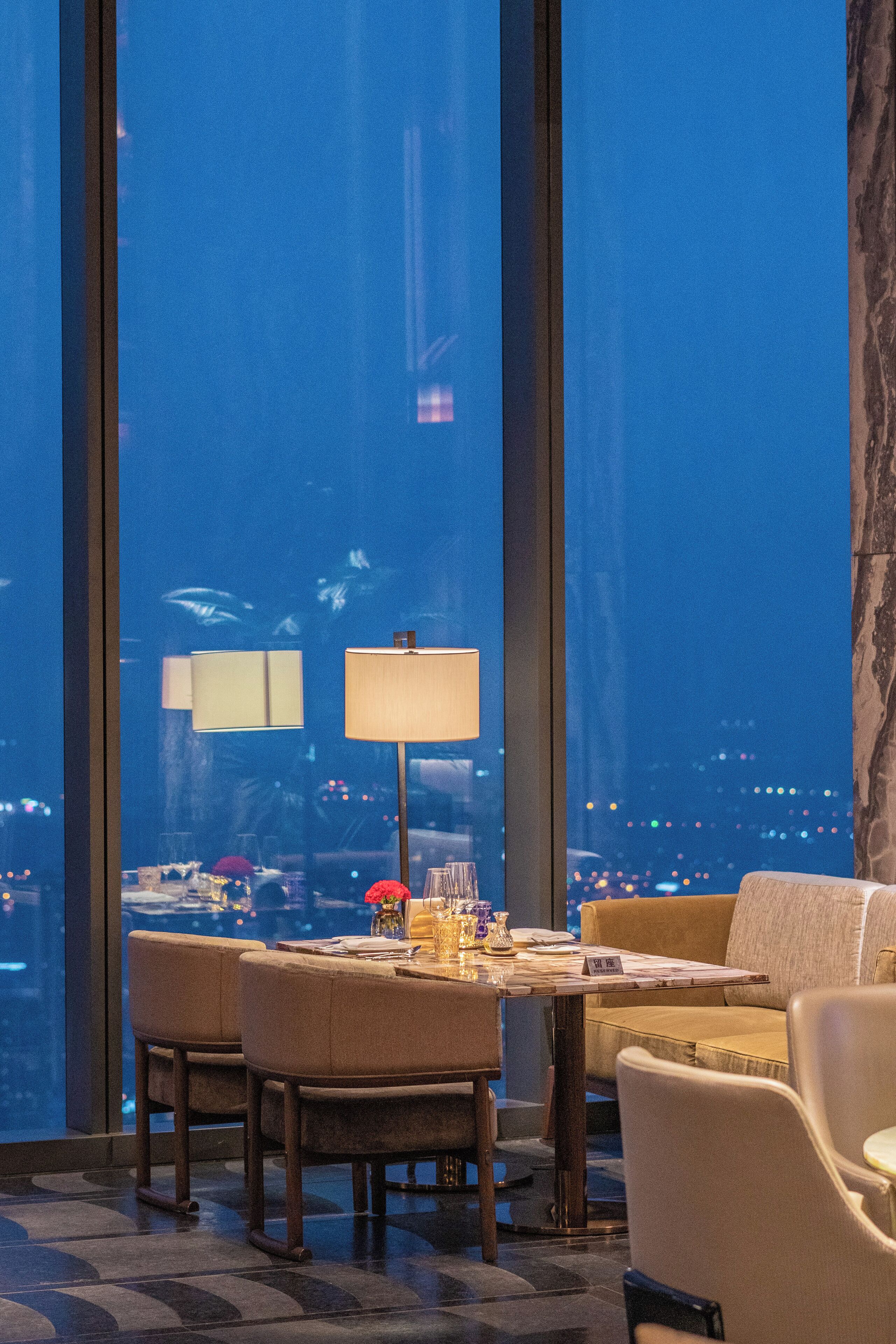 Ein Essbereich mit Tisch und Stühlen, einer Couch und einem großen Fenster mit Blick auf die Stadt.